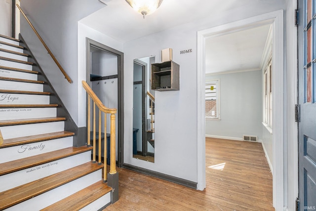 stairs with hardwood / wood-style flooring and crown molding