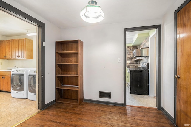 washroom featuring washing machine and dryer, cabinets, and hardwood / wood-style floors