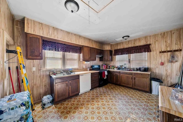 kitchen with wooden walls, white dishwasher, electric range, and sink