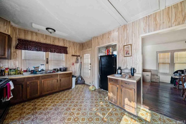 kitchen with black fridge, range with electric stovetop, and wood walls