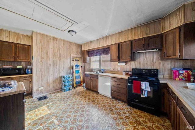 kitchen featuring dark brown cabinets, wooden walls, and black appliances