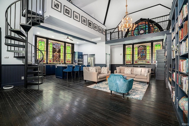 living room featuring ceiling fan with notable chandelier, dark wood-type flooring, and a towering ceiling