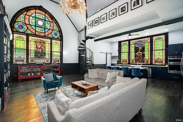 living room with ceiling fan with notable chandelier, dark hardwood / wood-style floors, and a towering ceiling