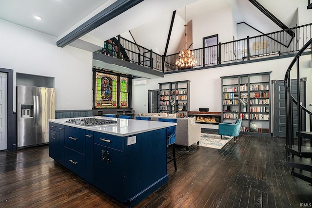 kitchen featuring dark hardwood / wood-style floors, a kitchen island, a towering ceiling, appliances with stainless steel finishes, and blue cabinets