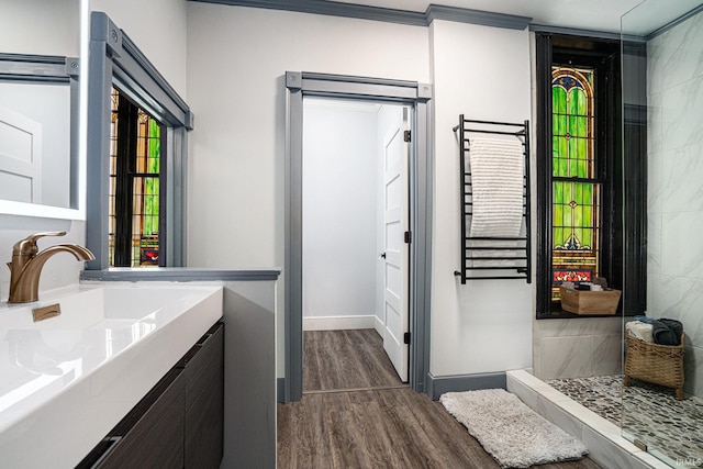 bathroom with hardwood / wood-style floors, walk in shower, vanity, and crown molding