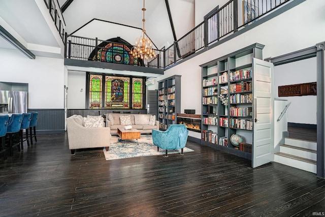 living area with dark wood-type flooring, an inviting chandelier, and a towering ceiling