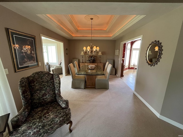 carpeted dining room with a wealth of natural light, a chandelier, a raised ceiling, and ornamental molding