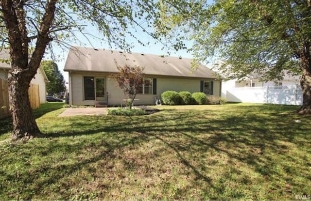 rear view of house with a lawn and a patio