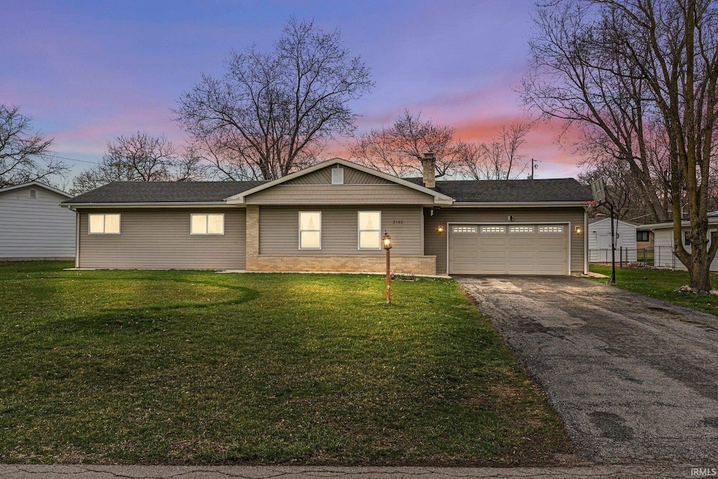 ranch-style house with a garage and a lawn