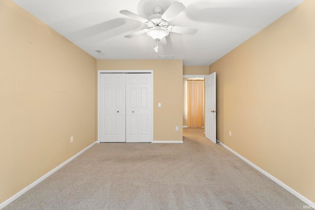 unfurnished bedroom featuring ceiling fan, a closet, and light colored carpet