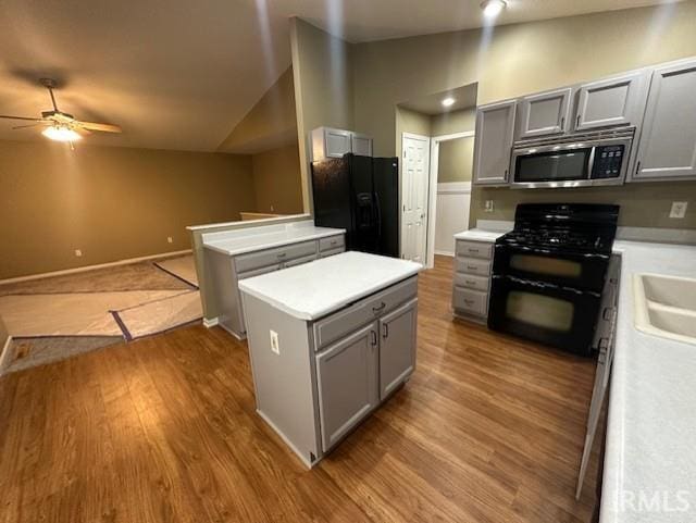 kitchen with gray cabinets, black appliances, and vaulted ceiling