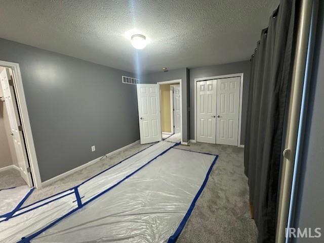 unfurnished bedroom with a textured ceiling, a closet, and carpet