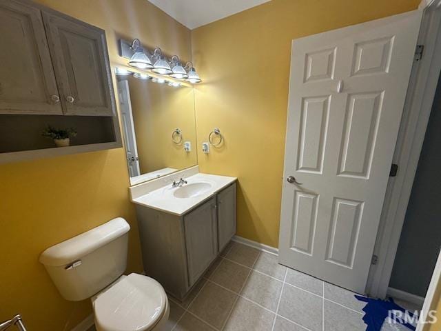 bathroom with toilet, vanity, and tile patterned flooring