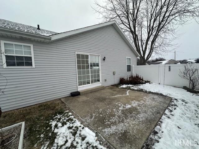 snow covered rear of property featuring a patio area