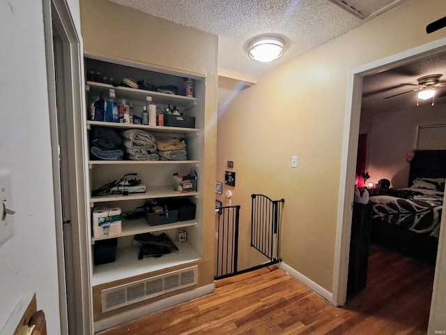 interior space with hardwood / wood-style flooring, a textured ceiling, built in features, and ceiling fan