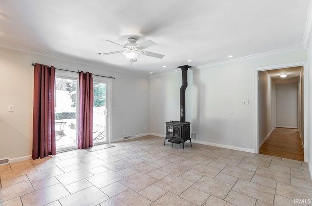 unfurnished living room featuring ceiling fan, a wood stove, and crown molding