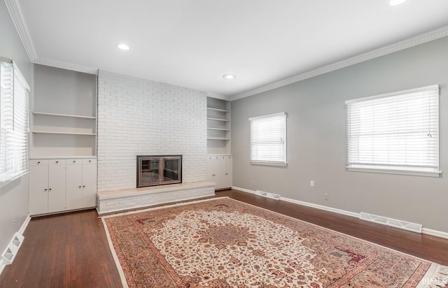 unfurnished living room with a brick fireplace, dark hardwood / wood-style floors, built in features, and ornamental molding