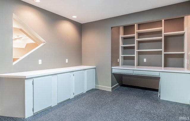 unfurnished office featuring built in desk and dark colored carpet