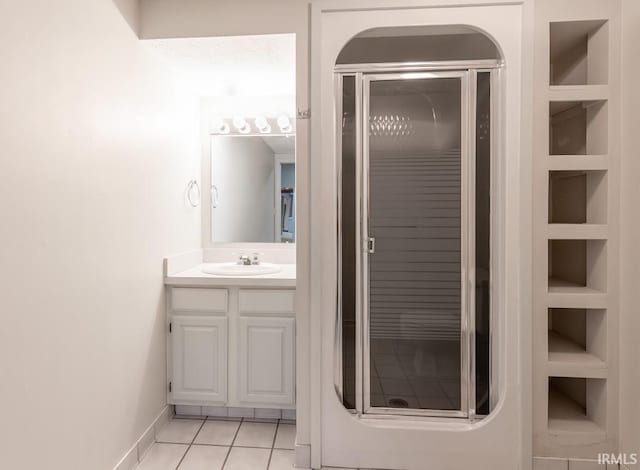 bathroom featuring a shower with shower door, vanity, tile patterned flooring, and built in features