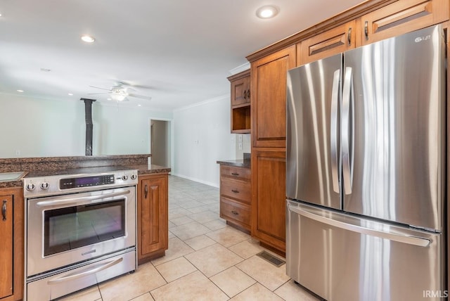 kitchen with appliances with stainless steel finishes, dark stone counters, light tile patterned flooring, ceiling fan, and crown molding