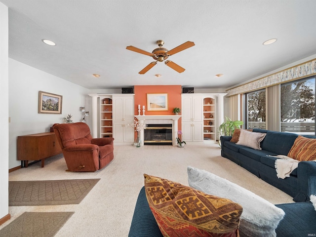 carpeted living room with ceiling fan and a tiled fireplace