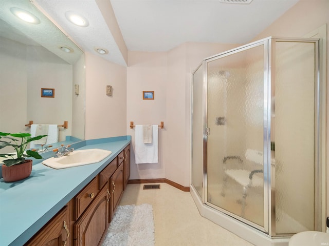 bathroom with a shower with shower door and vanity