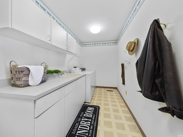 laundry area featuring cabinets, washer and clothes dryer, and sink