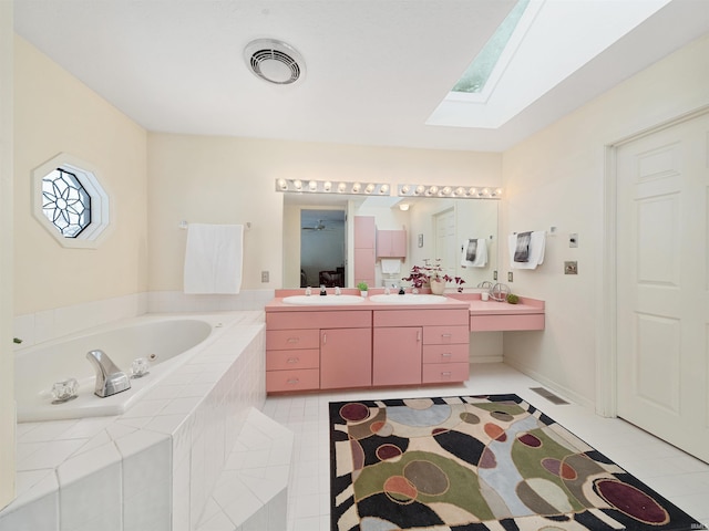 bathroom featuring a relaxing tiled tub, tile patterned floors, vanity, and a skylight