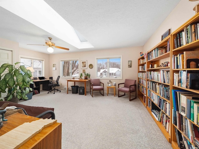 living area with carpet floors, a wealth of natural light, a textured ceiling, and ceiling fan