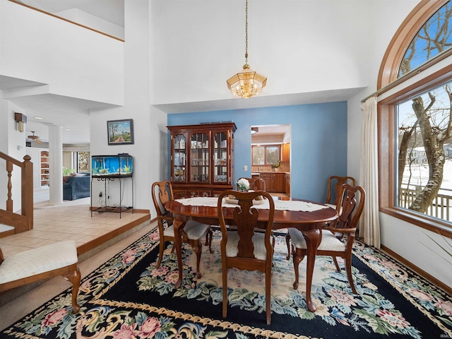 tiled dining area with an inviting chandelier, a towering ceiling, and a healthy amount of sunlight