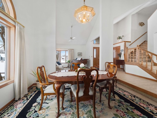 dining area with high vaulted ceiling and ceiling fan with notable chandelier