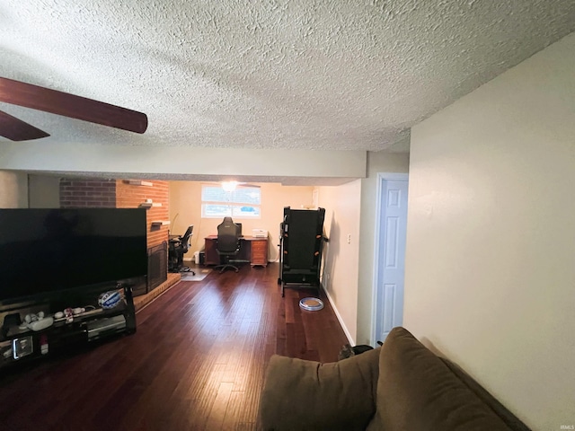 living room with a textured ceiling, dark wood-type flooring, and ceiling fan