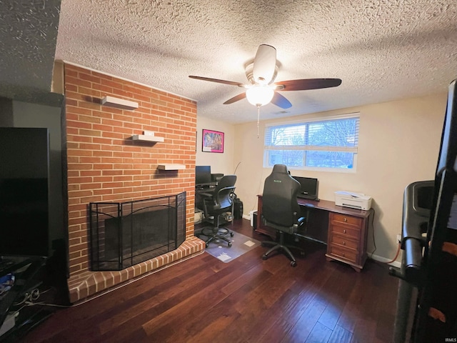 office space with ceiling fan, a brick fireplace, a textured ceiling, and dark hardwood / wood-style floors