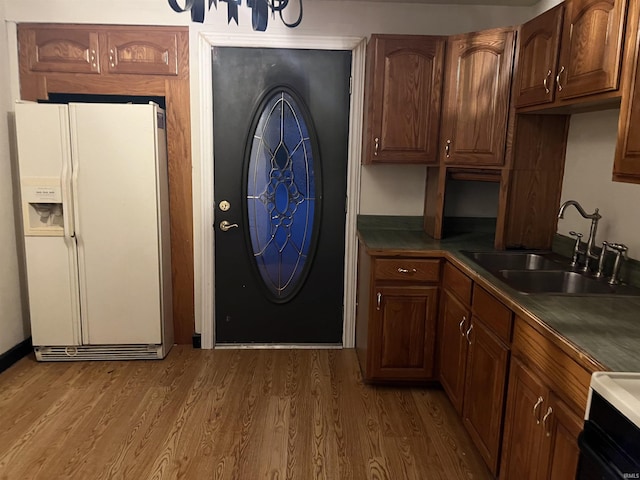 kitchen featuring stove, sink, dark wood-type flooring, and white fridge with ice dispenser