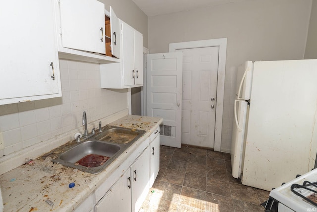 kitchen with freestanding refrigerator, white cabinets, a sink, and decorative backsplash