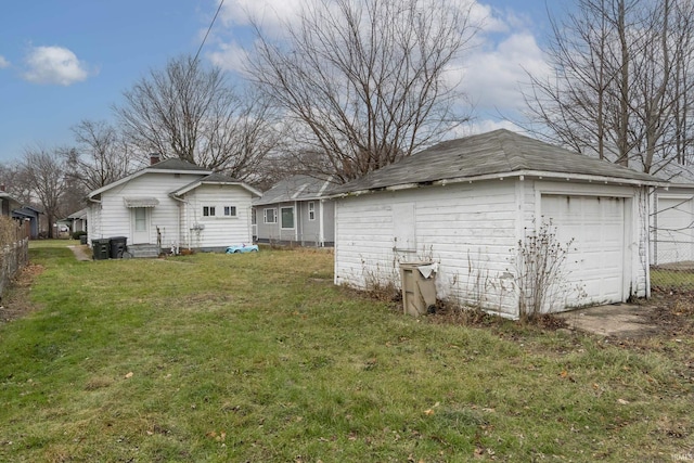 back of house with a garage, an outbuilding, and a yard