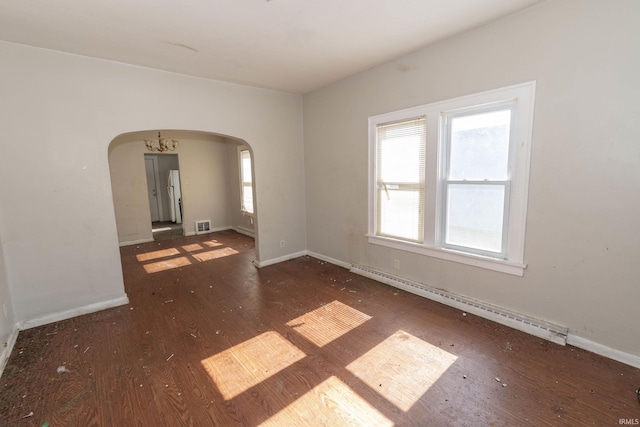 spare room with arched walkways, a baseboard radiator, dark wood finished floors, and a healthy amount of sunlight