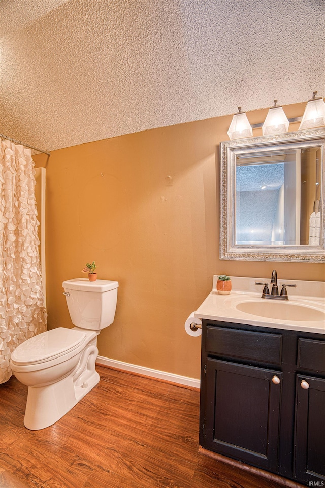 bathroom with toilet, vanity, a textured ceiling, and hardwood / wood-style flooring