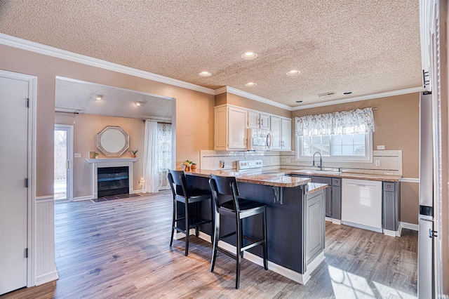 kitchen featuring backsplash, dishwasher, a kitchen island, a kitchen bar, and white cabinets