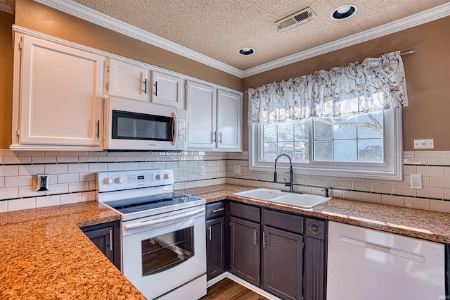 kitchen with white appliances, a textured ceiling, ornamental molding, white cabinets, and sink