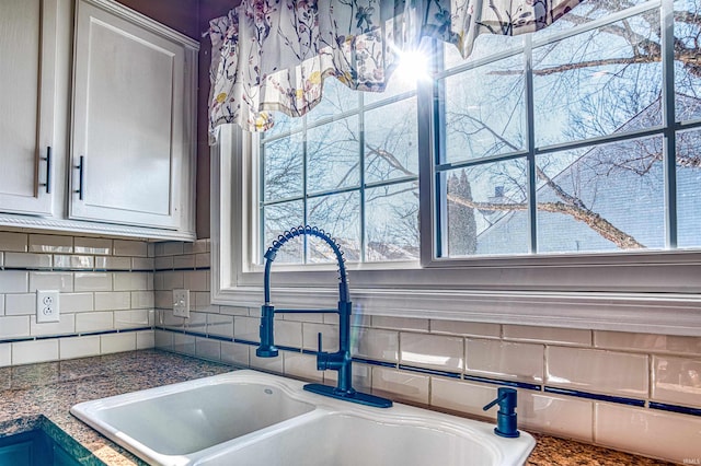 room details featuring sink, backsplash, and white cabinets