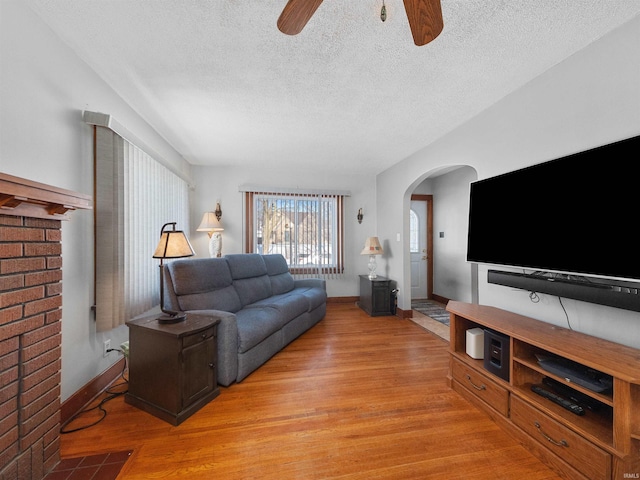 living room featuring ceiling fan, a textured ceiling, and light hardwood / wood-style flooring