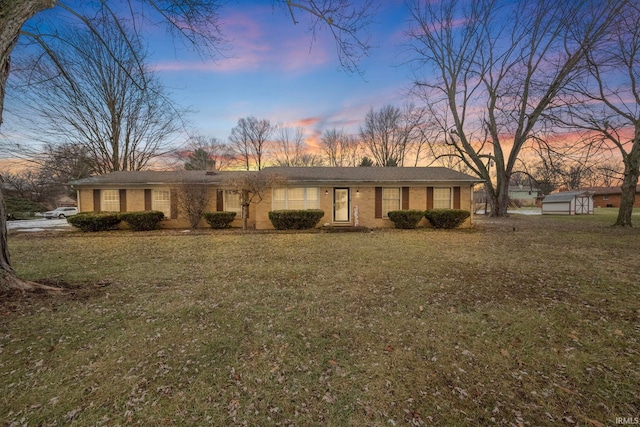 ranch-style house with a storage unit and a yard