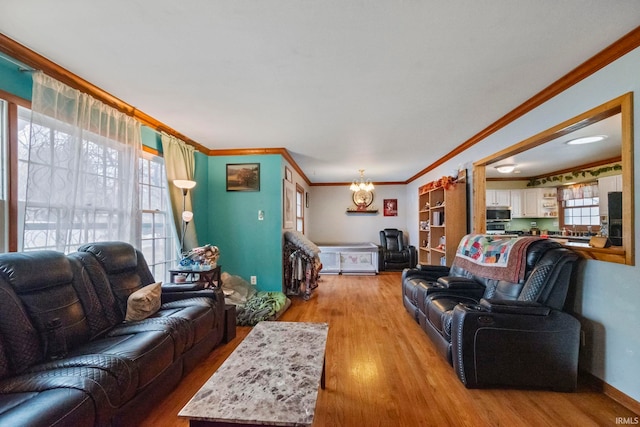 living room featuring light wood-type flooring, plenty of natural light, ornamental molding, and a notable chandelier