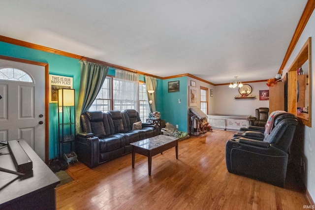 living room with wood-type flooring, crown molding, and an inviting chandelier