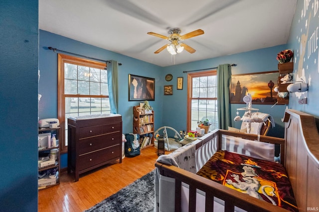 bedroom featuring ceiling fan, light hardwood / wood-style floors, and multiple windows