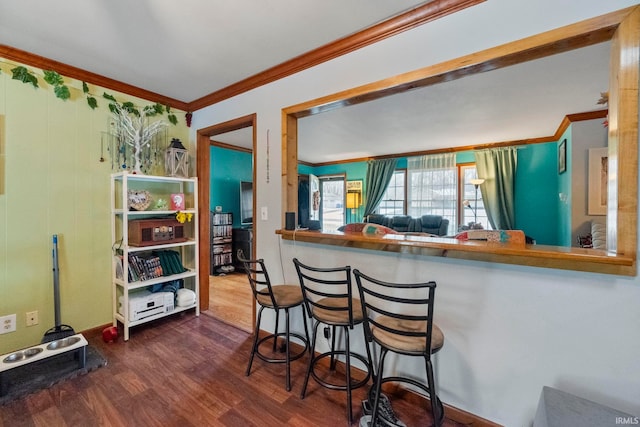 kitchen featuring dark hardwood / wood-style floors, crown molding, and a breakfast bar area