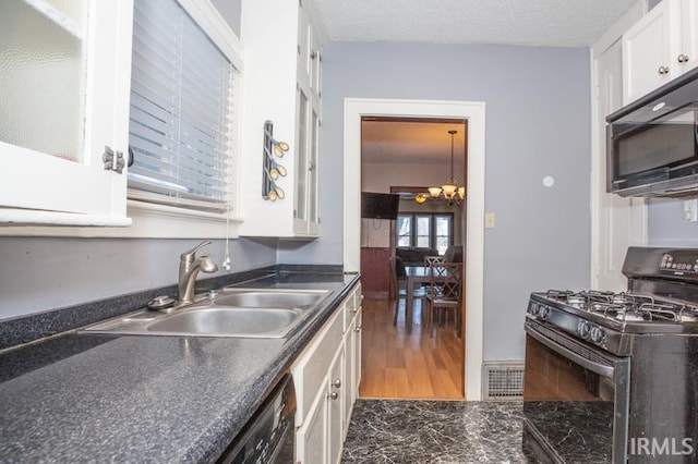 kitchen featuring a textured ceiling, white cabinets, black appliances, sink, and a chandelier