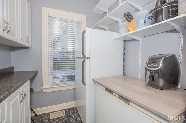 interior space featuring white cabinets and white refrigerator