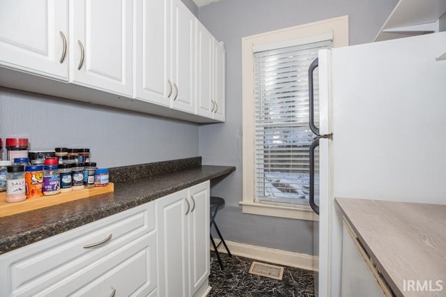 kitchen featuring white cabinets and white fridge